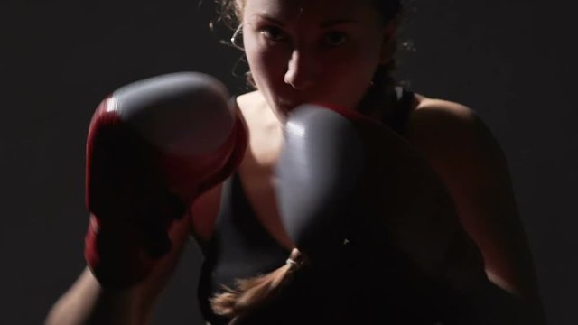 Strongly motivated girl boxing in the gym, female athlete preparing for fight