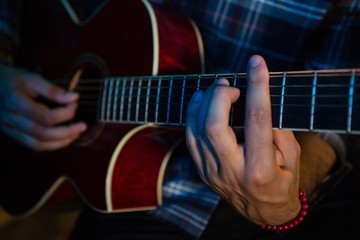 Mid section of musician playing guitar on stage