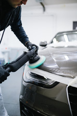 Car detailing - Hands with orbital polisher in auto repair shop. 