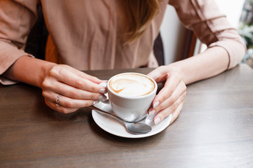 Beautiful cute girl in the cafe near the window with coffee smiling