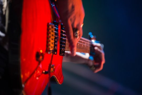 Close-up of guitarist playing guitar on stage