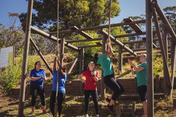 Female trainer instructing women to climb a rope 