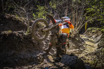 Tuinposter Motocross rider passes through the mud on the hardenduro race © Glasco