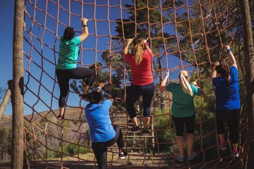 Group of fit woman climbing a net during of course