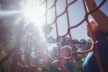Two fit women climbing a net during obstacle course training