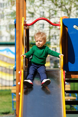 One year old baby boy toddler wearing green sweater at playground