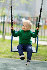 One year old baby boy toddler wearing green sweater at playground