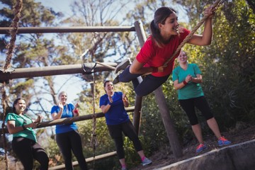 Fit woman climbing a rope during obstacle course training