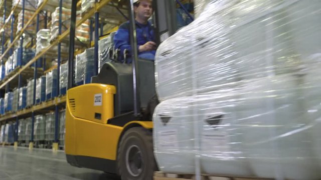 Forklift operator transporting cargo in warehouse