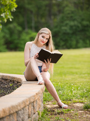 Teenage girl with a book in the park during the summer.