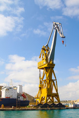 Fototapeta na wymiar Huge port crane near the docks, which is a modern ship.. Malta.