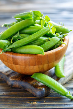 Wooden bowl with green pea pods.