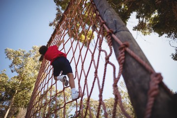 Boy climbing a net during obstacle course