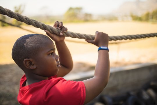Determined boy crossing the rope during obstacle course