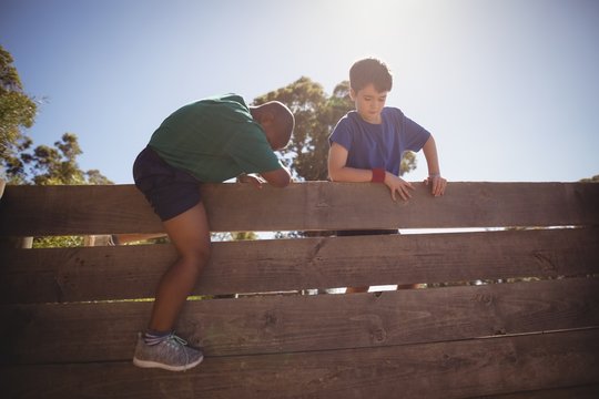 Kids climbing wooden wall during obstacle course