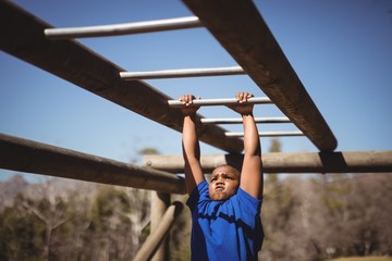 Determined boy exercising on monkey bar during obstacle course