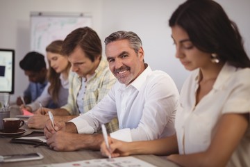 Mature businessman with colleagues in conference room