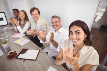 Smiling business people applauding during presentation in office
