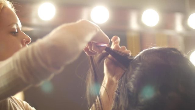 Hairdresser curling hair to foxy girl in beauty salon Close up Slow motion