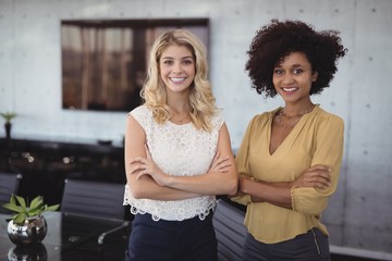 Smiling female colleagues standing in meeting room at office