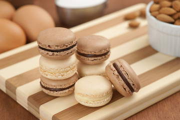 Chocolate and Vanilla Macarons with Ingredients on Striped Board