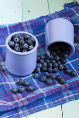 Blueberries in cup. Blue wooden table, blue kitchen towel.