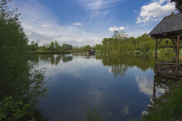 Obraz premium Landscape. The small lake with the wood on the horizon. The house at water.