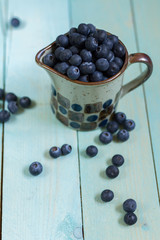 Blueberries in cup. Blue wooden table, blue kitchen towel.