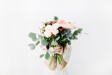 Pretty woman with beautiful flowers bouquet at white wall. Lifestyle composition.