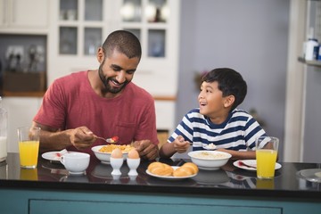 Fototapeta na wymiar Happy man with his son having breakfast in kitchen
