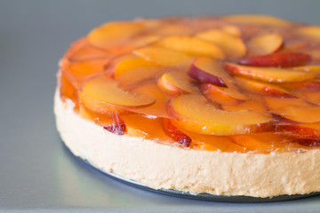Fruit cake with peach, jelly and mousse in plate on gray background.