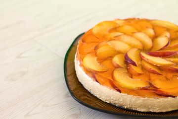 Fruit cake with peach, jelly and mousse in plate on wooden background.
