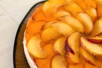 Fruit cake with peach, jelly and mousse in plate on wooden background.