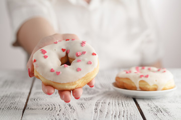 junk-food and eating concept - close up of female hand holding glazed donut