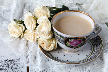 cup of coffee and a bouquet of white roses