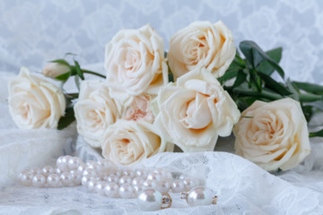 White fresh flowers with pearls jewellery on white wooden table with copy space