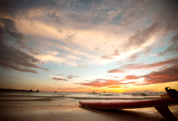 surfboard on the shore at sunset