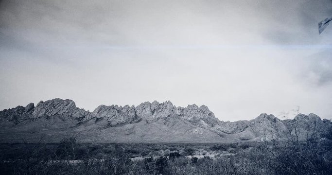 Mountains Windmill and Flair Styled Time-lapse. a panning time-lapse of an old windmill in the desert with mountains in the background. Ominous and styled unique with grain and old feel
