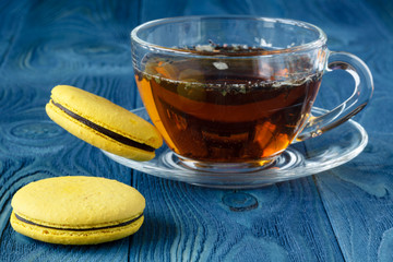 Cup of tea with french macaroon on dark background.