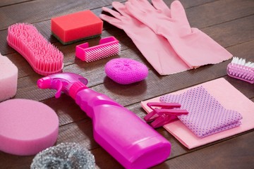 Pink color cleaning equipment arranged on wooden floor