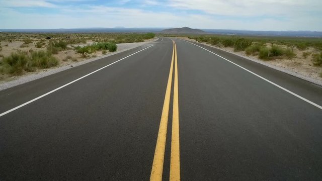 Empty Desert Road Middle During Daytime. view moving up the middle of a highway road in the desert during daytime. Slow motion
