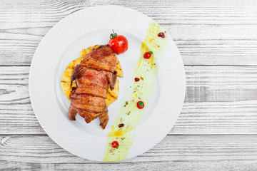 Roasted Pork steak on bone stuffed with cheese, grilled vegetables and berries on stone slate background on wooden background close up. Hot Meat Dishes. Top view with copy space