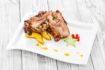 Roasted Pork steak on bone stuffed with cheese, grilled vegetables and berries on stone slate background on wooden background close up. Hot Meat Dishes. Top view with copy space