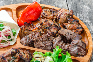 Roasted Pork steak on bone stuffed with cheese, grilled vegetables and berries on stone slate background on wooden background close up. Hot Meat Dishes. Top view with copy space