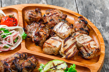 Roasted Pork steak on bone stuffed with cheese, grilled vegetables and berries on stone slate background on wooden background close up. Hot Meat Dishes. Top view with copy space