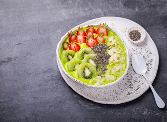 Breakfast Detox Green Smoothie  Bowl with fresh berries,kiwi and chia seeds. Food or Healthy diet concept on the gray background.Super Food.selective focus.