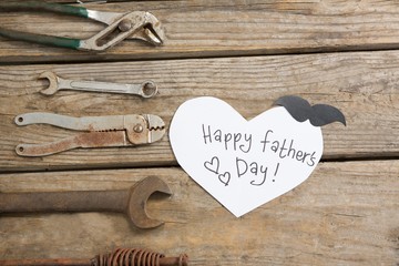 Overhead view of happy fathers day text by work tools on table