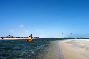 A traditional fishing boat sails along the ocean channel to the tide in Atins, Lencois Maranhenses National Park, Brazil