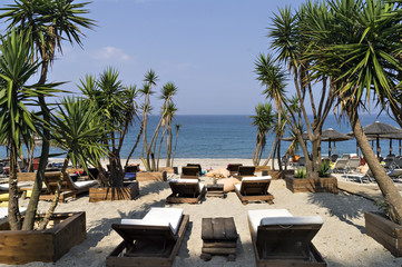 Beautiful Ionian sandy resort beach in Greece with sunbeds and sunshades. Vacation destination. Public beach