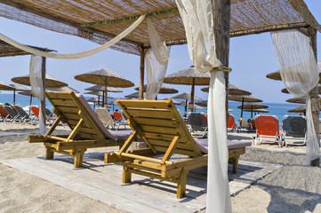 Beautiful Ionian sandy resort beach in Greece with sunbeds and sunshades. Vacation destination. Public beach
